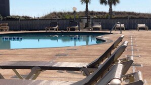 A pool area with lounge chairs and a palm tree in the background.