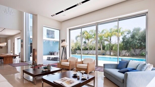 A modern living room with a pool view, a dining area, and a large window. - Luxurious villa with fenced swimming pool in the Caesarea Golf area  (Caesarea)