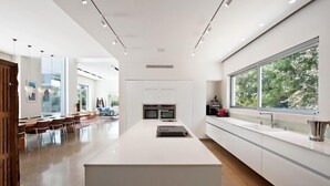 A modern kitchen with a central island, built-in appliances, and large windows offering a view of greenery. - Luxurious villa with fenced swimming pool in the Caesarea Golf area  (Caesarea)