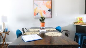 A dining area with a wooden table, blue chairs, a potted plant, and a welcome book. - “Ca C’est Bon” (Lake Charles)