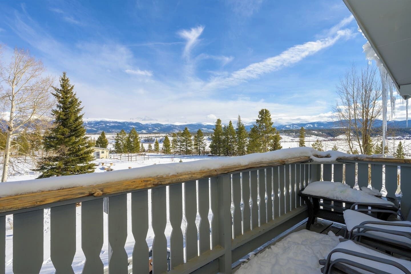A balcony with a view of snow-covered landscape and mountains.