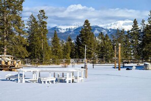 A snow-covered outdoor area with picnic tables and a view of snow-capped mountains.