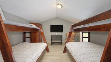 Ein Schlafraum mit zwei Etagenbetten, einem an der Wand befestigten Fernseher und einem kleinen Schreibtisch mit Stuhl.