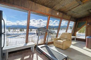 A room with a treadmill, a recliner, and large windows offering a view of a snowy landscape. - Rustic 11BR Estate, Sleeps 36, Weddings + Free Belize Week (Fraser)