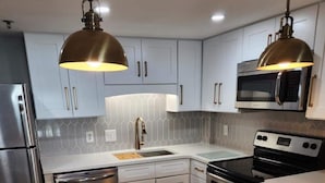 A modern kitchen with white cabinets, stainless steel appliances, and a marble countertop. - GORGEOUS View of Ocean, Coast & Sunset! - Remodeled Forest Dunes (Myrtle Beach)