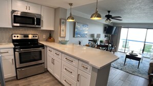 A modern kitchen with white cabinetry, stainless steel appliances, and a large island. - GORGEOUS View of Ocean, Coast & Sunset! - Remodeled Forest Dunes (Myrtle Beach)