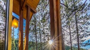 Um deck de madeira com cadeiras Adirondack, uma churrasqueira e vista para uma área arborizada.