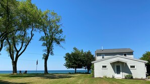 A small white building with a gabled roof, surrounded by a grassy lawn and trees. - Lake Ontario waterfront home, close to Erie Canal & Niagara Falls (Lyndonville)