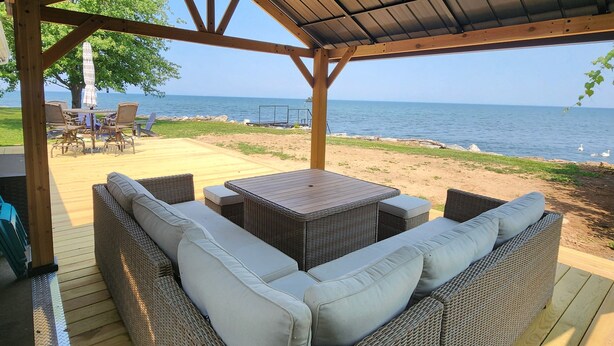 A covered outdoor seating area with wicker furniture and a view of the sea. - Lake Ontario waterfront home, close to Erie Canal & Niagara Falls (Lyndonville)