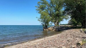 A public beach with a rocky shoreline and trees along the water's edge. - Lake Ontario waterfront home, close to Erie Canal & Niagara Falls (Lyndonville)