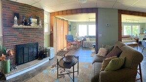 A living room with a fireplace, a sofa, a coffee table, and a dining area with chairs. - Lake Ontario waterfront home, close to Erie Canal & Niagara Falls (Lyndonville)