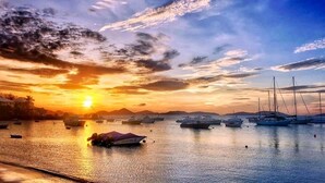 A marina with boats docked, a sunset in the background, and a person in a kayak. - Grande Bay Luxury 3BR Spectacular Unobstructed View   (Cruz Bay)