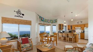 A spacious living area with a view of the ocean, a dining table, and a kitchen area. - Hale Kohola ~ Spacious, Super Views - 30 Day Minim (Waimea)