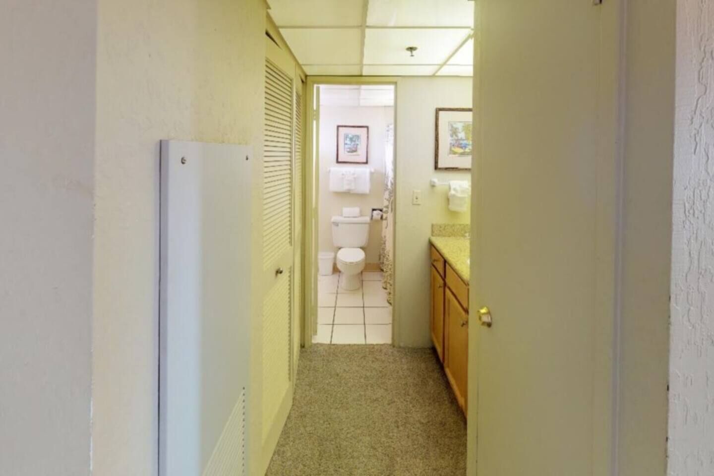 Ein schmaler Flur, der zu einem Badezimmer mit Toilette und Waschbecken führt.