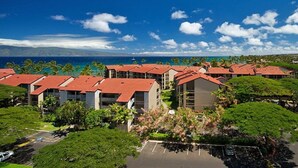 A resort with multiple buildings, a parking area, and a view of the ocean.
