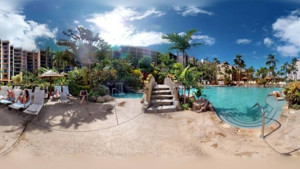 A resort with a pool, lounge chairs, and a staircase leading to the pool.
