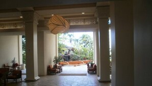 A lobby with a stone floor, columns, seating, and a view of a waterfall.