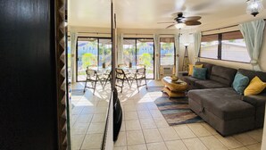 A spacious living area with a sofa, a dining table with chairs, and a ceiling fan. - Maui Special!! 2BDRM/2BA Ocean View and Convenient Location (Kihei)