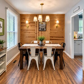 A dining area with a wooden table, white chairs, and a chandelier. - Misty Court Hideaway Cozy + Private Retreat (Nashville)