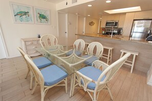 Enjoy meals in the kitchen with a central island and dining area featuring a glass-top table and wicker chairs.