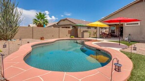Un jardin à l’arrière de la maison avec une piscine, du mobilier de jardin et un petit potager.