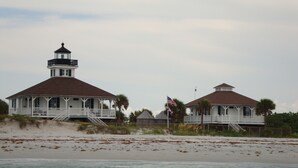 Una casa costera con una torre de faro, un balcón y una bandera.