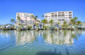 A waterfront hotel with multiple floors, a marina with boats, and palm trees. - Seeing is Believing! Incredible Boca Vista Harbor Waterfront Condo! (Placida)