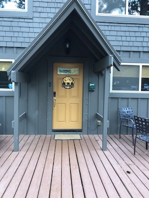 A wooden door with a mountain design, a porch with a bench, and a window with a view.