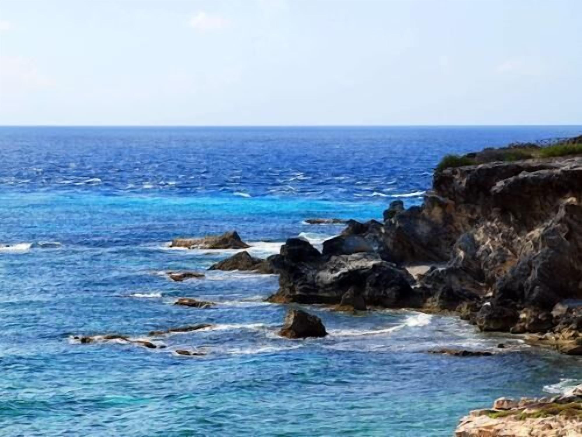 Un paysage côtier caractérisé par un terrain rocheux et des eaux d’un bleu limpide.