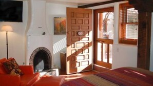 Una habitación acogedora con chimenea, una puerta de madera y una ventana.