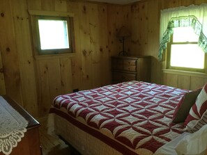 A wooden-paneled room with a bed, a dresser, and a window with curtains. - Paddle, float, fish, or rope swing into the lake. Direct ATV trail access too! (Strong)