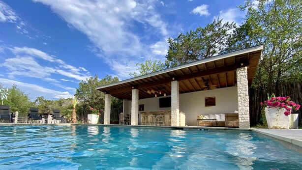 A swimming pool with a covered patio area, stone pillars, and outdoor seating. - Historic Gated Estate, Pool, Cabana, 2 Kitchens, Lush, Kayaks, Walk 2 Frio! (Concan)