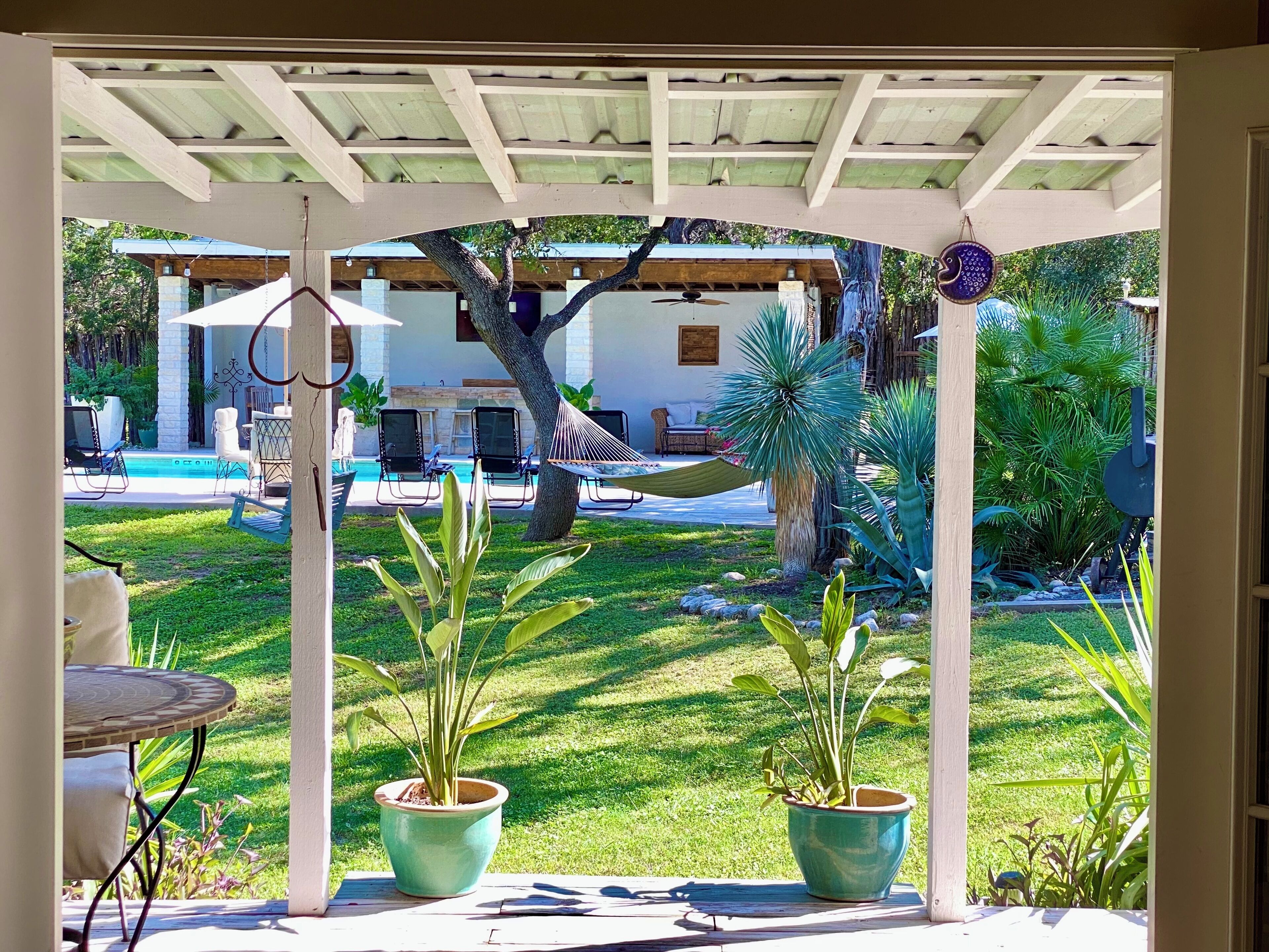 Un patio techado con piscina, mobiliario exterior y plantas en macetas.