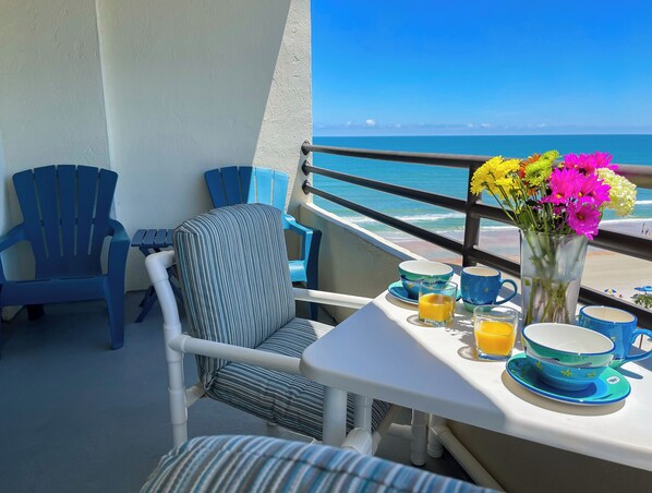 A balcony with a table set for breakfast, chairs, and a view of the ocean. - Newly Renovated Oceanfront Pool & Deck- GORGEOUS Ocean Views!!! (Daytona Beach Shores)