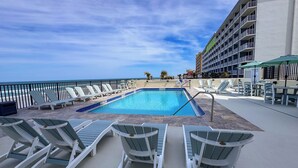 Zona junto a la piscina con sillones de descanso, piscina y vista a la playa y al océano.