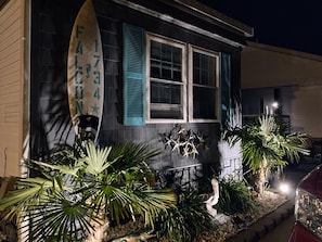 A house with a surfboard decoration, a window with shutters, and a statue of a pelican.