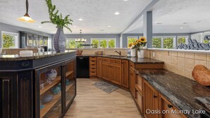 A modern kitchen with dark cabinetry, granite countertops, and a large island. - Oasis on Murray Lake, just NE of Grand Rapids (Lowell)