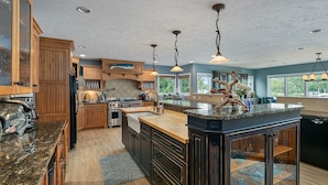 A spacious kitchen with wooden cabinets, granite countertops, and a large island. - Oasis on Murray Lake, just NE of Grand Rapids (Lowell)