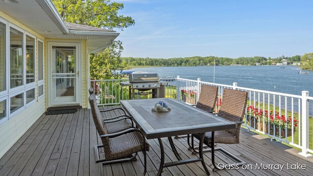 A deck with a table and chairs, overlooking a lake with a view of the surrounding landscape. - Oasis on Murray Lake, just NE of Grand Rapids (Lowell)