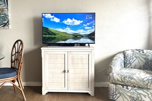 A television on a cabinet, a chair, and a patterned sofa in a room. - Ocean View, Fully Remodeled, New AC, Walk to Beach (Kihei)