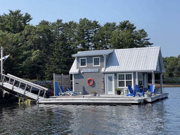 A floating cottage named Ketch Cottage with a dock, lounge chairs, and a lifebuoy. - Floating Cottage on The LaHave River close to beaches, golf, on Lighthouse Route (Pleasantville)