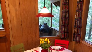 A dining table set with red placemats, white plates, and a vase of yellow tulips. - Cozy Riverfront Cabin Near Crystal Mountain & Sunrise Mt. Rainier National Park (Greenwater)