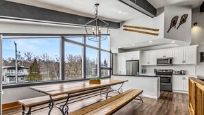 A modern kitchen with white cabinets, stainless steel appliances, and a wooden dining table.