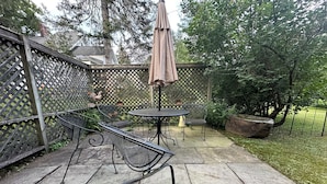 Eine Terrasse mit Tisch, Stühlen, einer Pergola und einem Zierzaun.