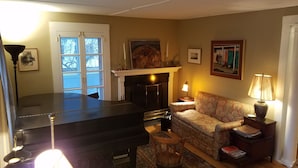 Ein Wohnzimmer mit Klavier, einer Couch, einem Kamin und einem Esstisch.