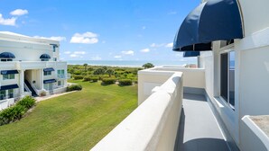 Ein modernes Hotel mit Balkon, der einen gepflegten Rasen und Meerblick bietet.