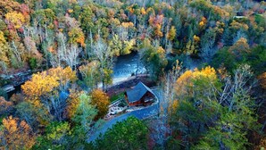 Eine Hütte, umgeben von einem Wald mit Herbstlaub.