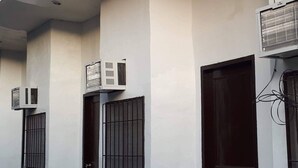 Un bâtiment doté de plusieurs unités de climatisation fixées sur les murs extérieurs, d’une série de portes et d’une conduite électrique visible.