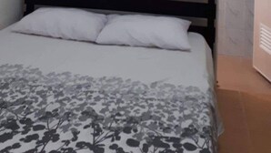 Une chambre à coucher avec un lit, une tête de lit en bois et une porte donnant sur une autre pièce.
