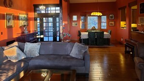A living room with a gray sofa, a coffee table, and a dining area with a table and chairs. - Spacious High Country Custom Home with Stunning Views (Williams)